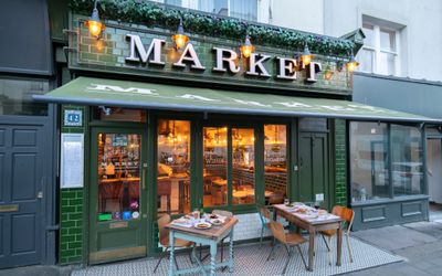 Green coloured entrance at market restaurant which is on Church Road in Hove. Voted 13th among the best restaurants in Brighton in 2023 at the Brighton restaurant awards. Market restaurant is described as Anglo-Spanish tapas and provides you with a social dining experience where you can watch the chefs at work. the sign above the restaurant is rescued from Camden market and the dining experience gives you the butcher, the fishmonger and the baker as part of the dining choices. the venue is owned by Neil Mannifield or Manni.