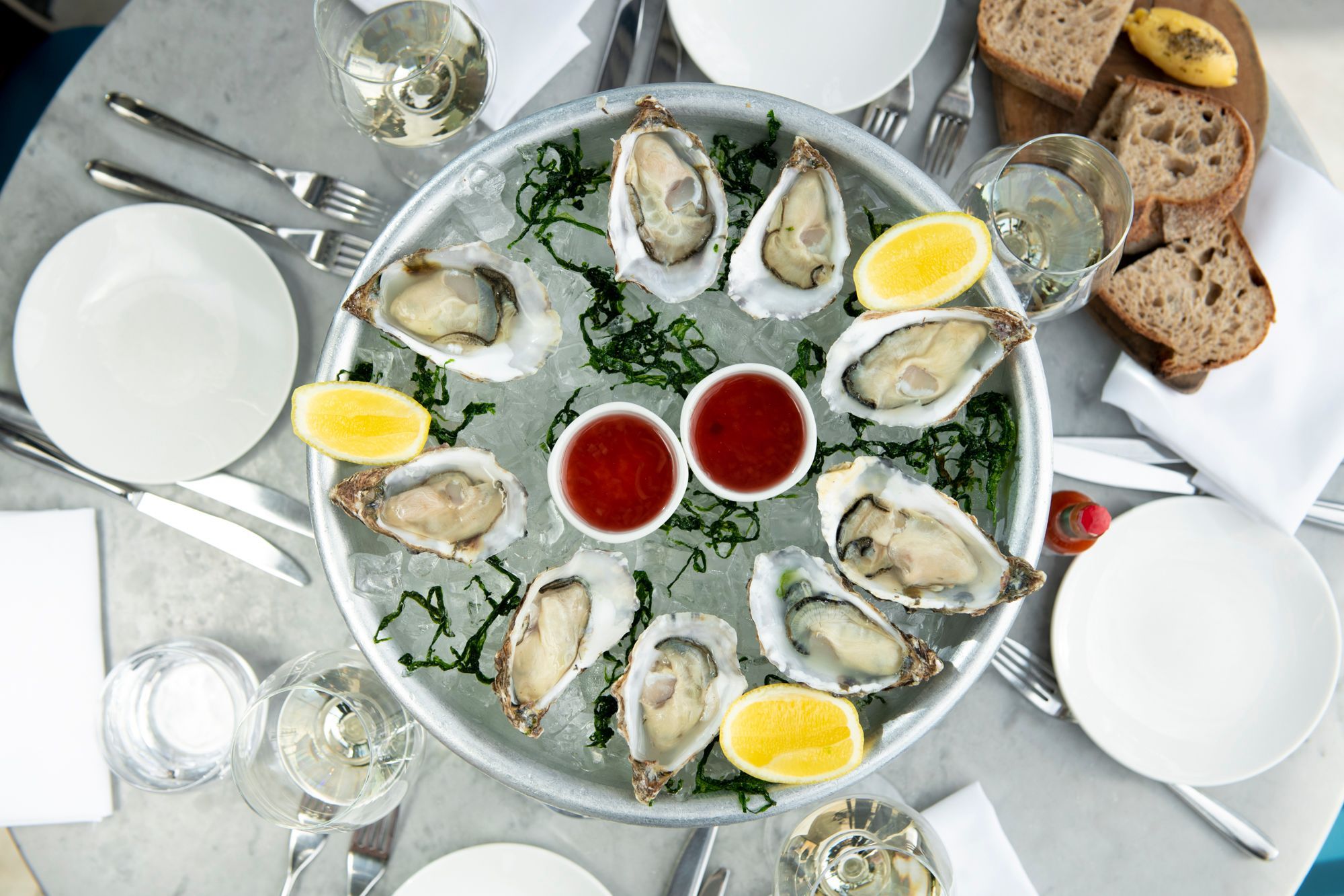 plate with oysters and lemons served with bread and white wine