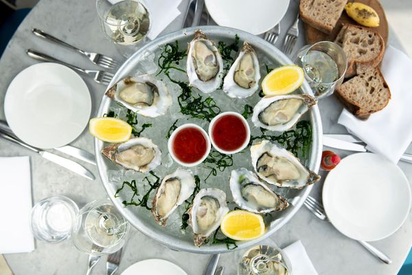 plate with oysters and lemons served with bread and white wine. Fish Brighton Restaurant, seafood restaurant. The Salt room is situated on Brightons seafront. fish restaurant Brighton