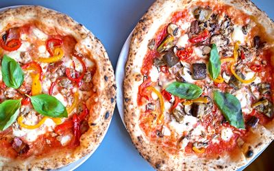 Overhead shot of colourful authentic Italian pizza garnished with fresh basil. Italian Restaurant Brighton