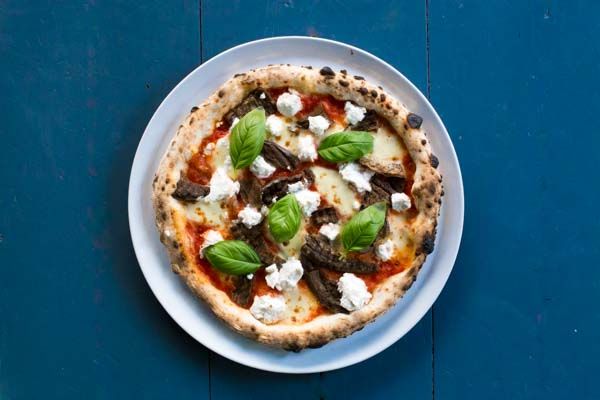 RB MARCH Sat 27th 3.55pm - Pizza picture from above against a blue table, topped with ricotta, fresh basil and tomato