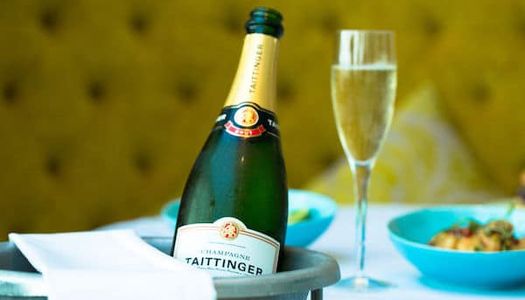 Christmas Shopping in Brighton, lunch, restaurants in Brighton. A bottle of champagne sitting in an ice bucket at the Grand Hotel Brighton. It is Tattinger Champagne, with a green banquet seating in the background. It is Christmas lunch Brighton