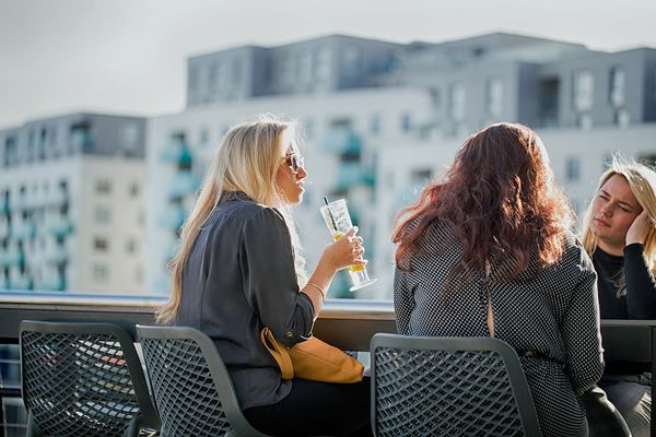 The Rooftop Terrace at Malmaison. One of the Brighton Marina Restaurants. Pictured two ladies sipping cocktails on the balcony at ChezMal restaurant. The ladies are wearing grey jackets on grey chairs.
