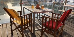 The Watershed. Brighton marina restaurant. Pictured, two wooden chairs with views over the Brighton marina. The sky is blue, the sun is shining and each of the chairs has a drink.. There are no people in the picture.