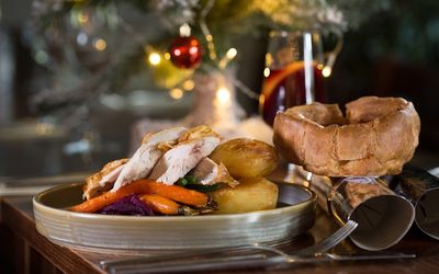 A turkey Christmas roast dinner at Hove Place Bistro and Gardens. Carrots, gravy a Yorkshire pudding, crackers and twinkly lights in the background. Hove Place is part of our Christmas Party Brighton guide