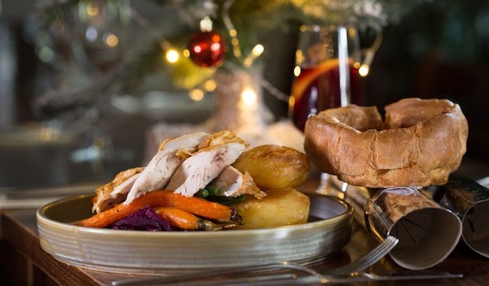 A turkey Christmas roast dinner at Hove Place Bistro and Gardens. Carrots, gravy a Yorkshire pudding, crackers and twinkly lights in the background. Hove Place is part of our Christmas Party Brighton guide