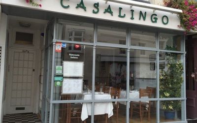 Restaurant exterior shot of Casalingo entrance and large window with hanging baskets.