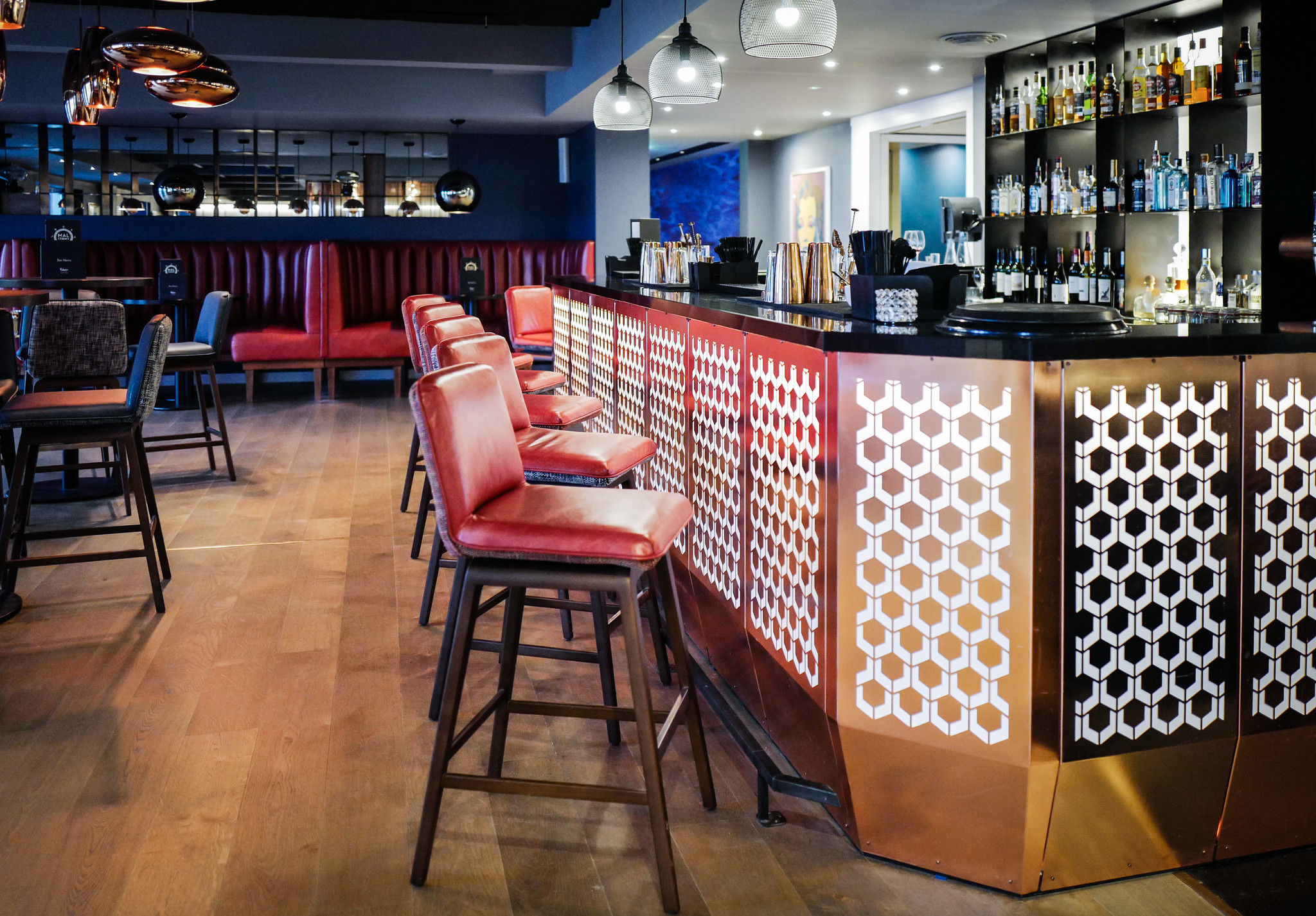 Malmaison Brighton. Interior shot of the bar area, golden and white bar with dark red bar stools