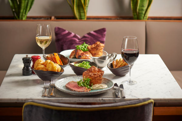 table at Malmaison Brighton laid out for two, Sunday roast served with glass of red and white wine