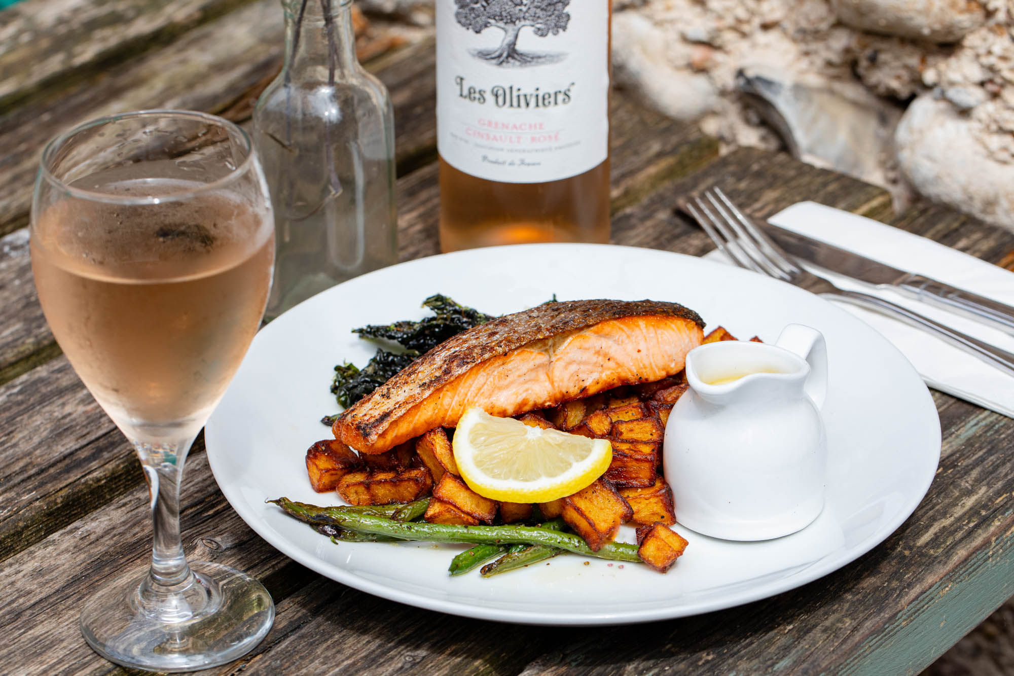 side shot of the salmon dish served with veggies and sparkling wine