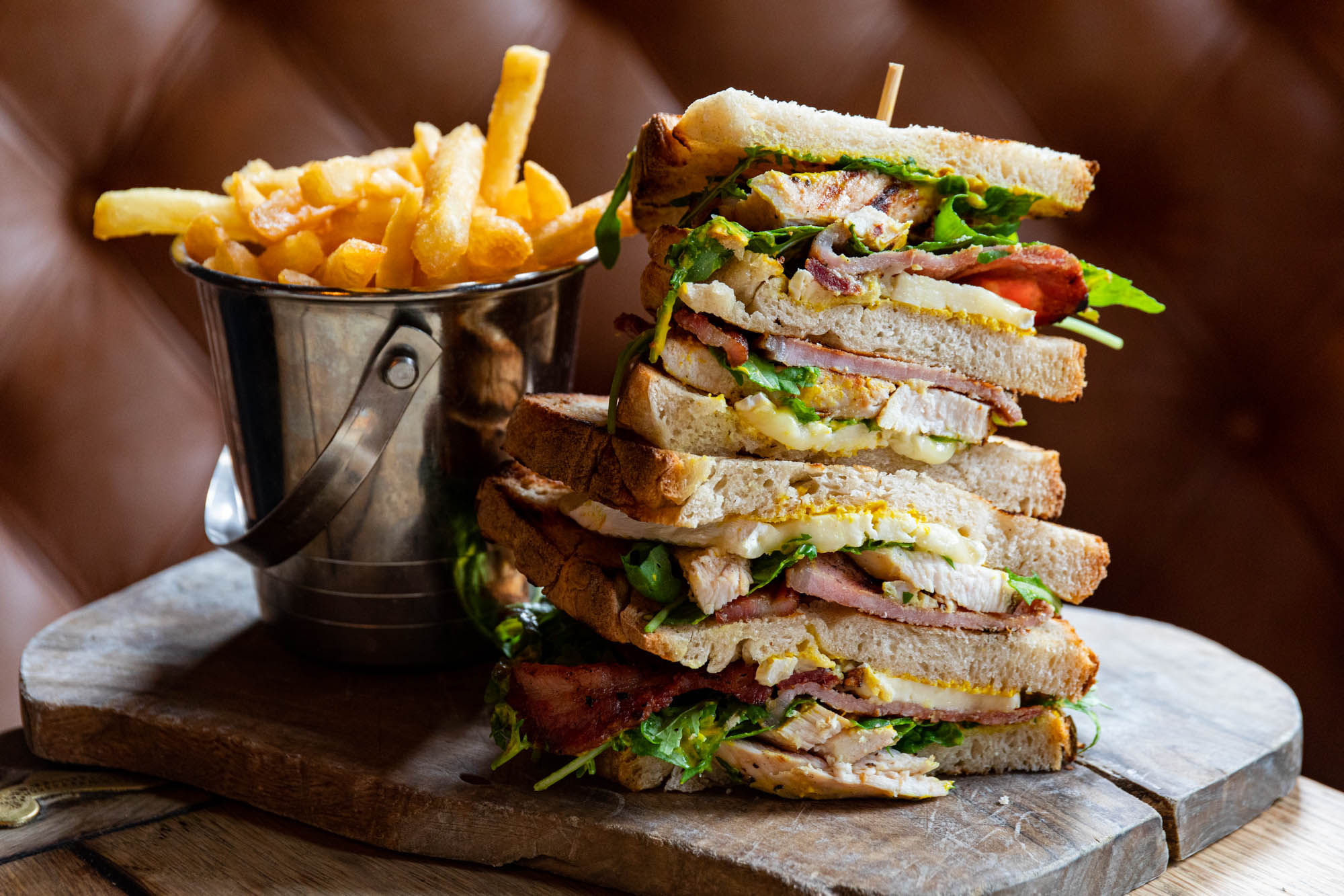 fries and big toast sandwich served on wooden plate. Better Half Pub