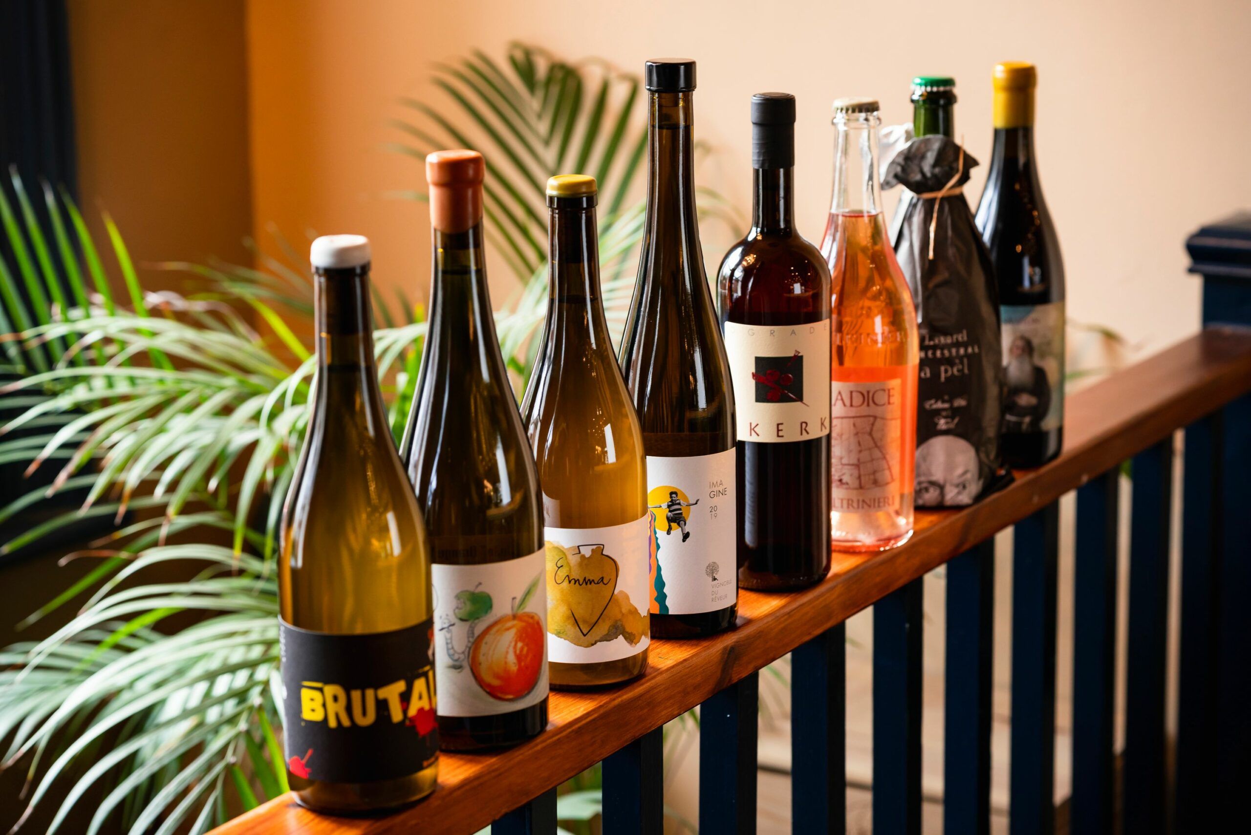 eight different wines next to each other on the wooden banister