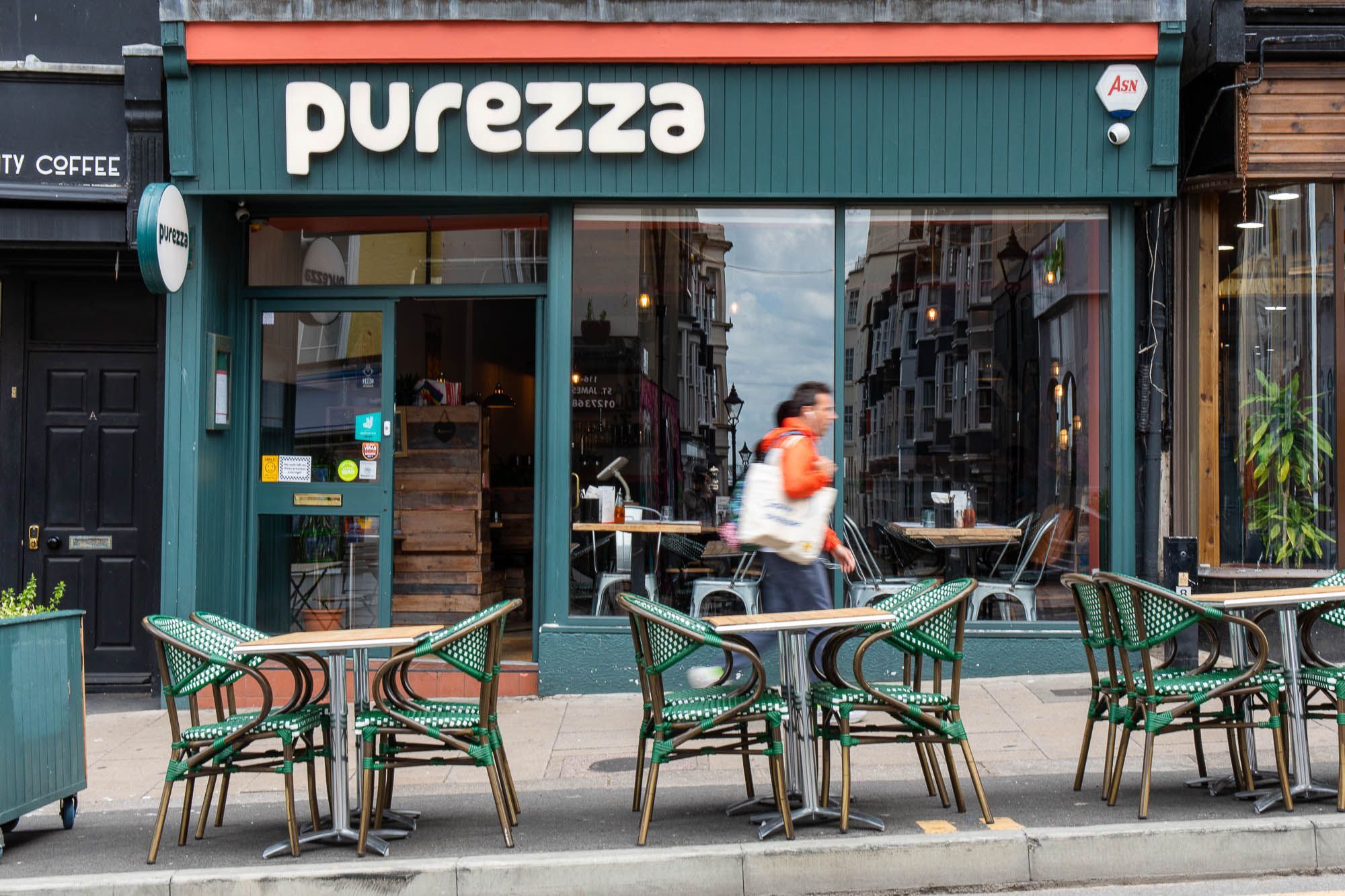 Purezza exterior, green venue with with sign, wooden chairs and tables with green covers