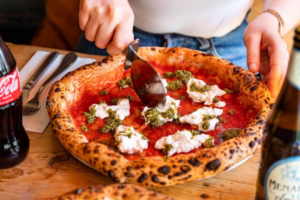 hand cutting vegan cheese and tomato pizza at Purezza Brighton