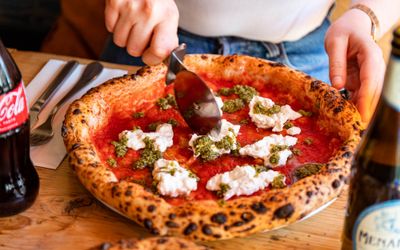 hand cutting vegan cheese and tomato pizza at Purezza Brighton