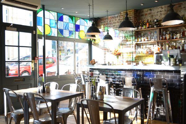 Plateau cocktail bar Brighton. Light coming in through the window. Tables and chairs in the foreground. Plateau showcase plenty of sharing plates and set menus in Brighton. 