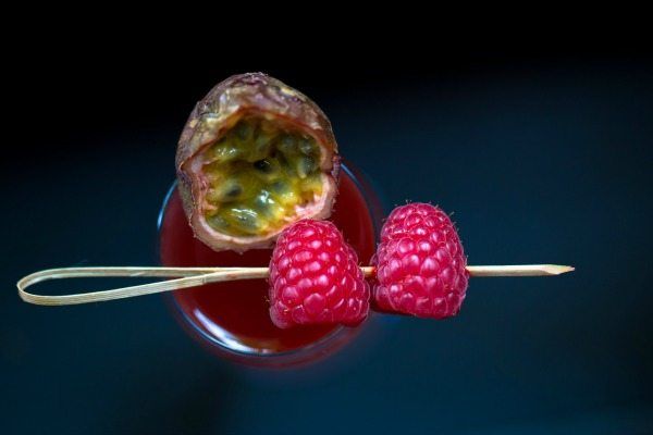 Rasberries in a cocktail with a very dark background