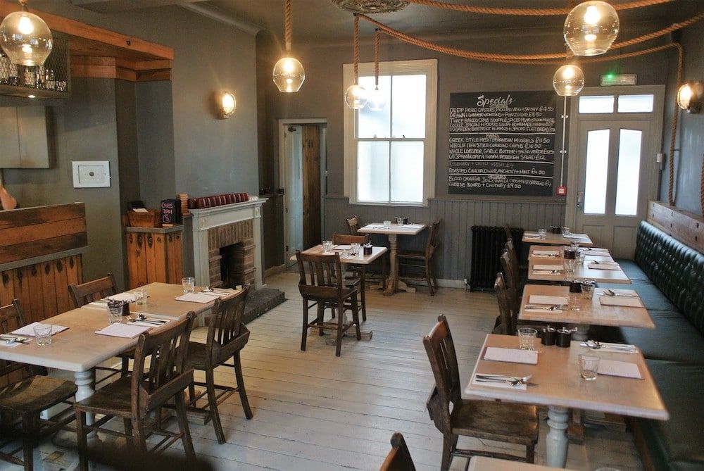 Inviting dining area at The Urchin Pub, part of a collection of Hove restaurants, featuring rustic wooden tables and soft pendant lights.
