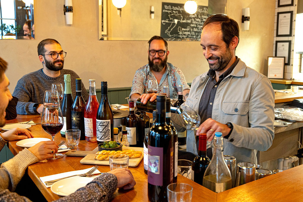 People sat around a counter with bottles and glasses of wine at Hove restaurant, Cin Cin.