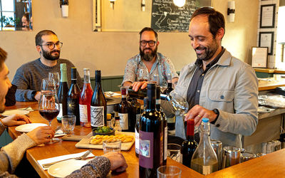 People sat around a counter with bottles and glasses of wine at Hove restaurant, Cin Cin.
