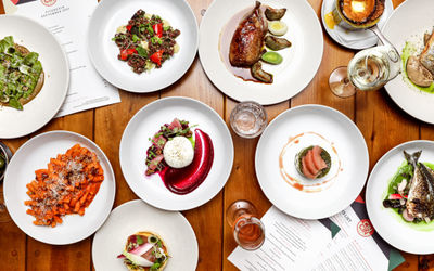 A selection of Italian small plates and pasta dishes laid out on a table on white plates