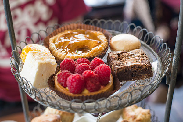 Afternoon tea patisserie tier including a raspberry tart, brownie, apple pie and macarons