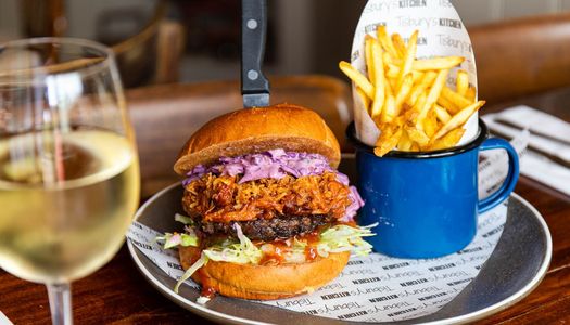 delicious looking burger with meat, red and green cabbage, cheese served with fries in blue cup