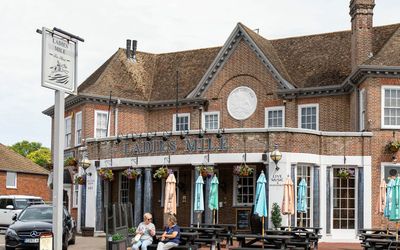 brown brick building of Ladies Mile in Patcham, black benches and tables, blue parasols