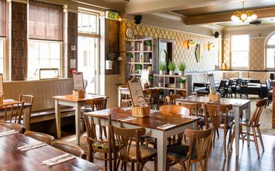 interior of the Ladies Mile pub in Patcham, wooden chairs and tables, wall with tapestry, low yellow lights. Available for private dining Brighton