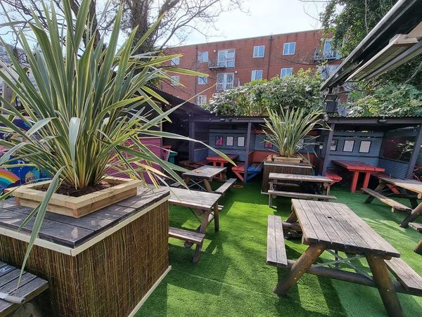An urban beer garden with pub benches, astroturf and booths