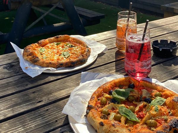 Two pizzas on a wooden pub garden bench