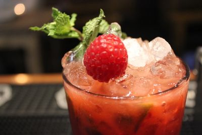 A raspberry cocktail with crushed ice and a spring of mint.