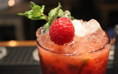 A raspberry cocktail with crushed ice and a spring of mint.