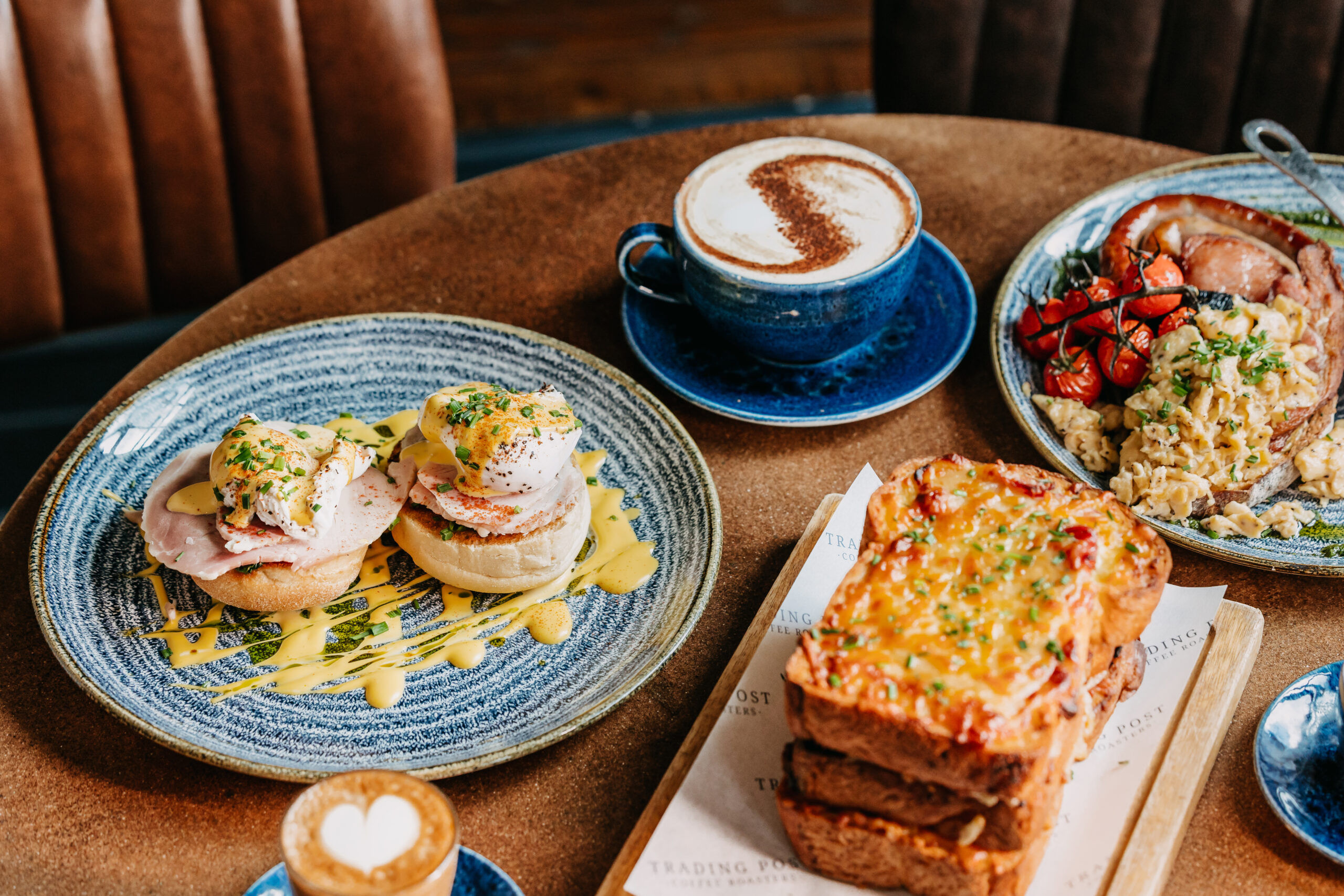 side shot of the couple of brunch dishes including toast, poached eggs, full english and coffees