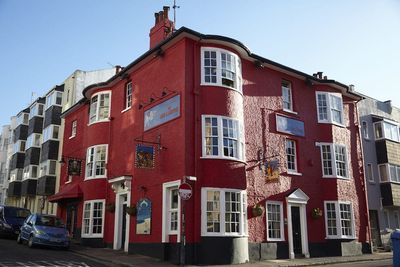 Exterior shot of the red painted Lion and Lobster pub on a sunny day with a clear blue sky.
