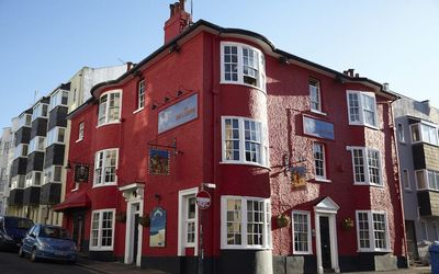 Exterior shot of the red painted Lion and Lobster pub on a sunny day with a clear blue sky.