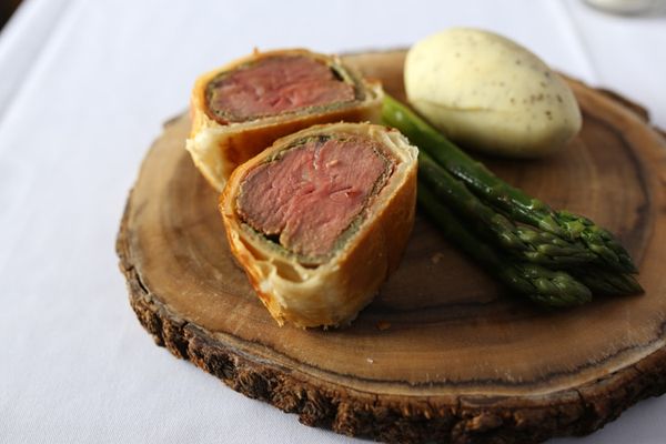Beef wellington served on wooden board at The Rose and Crown. Best restaurants in Sussex