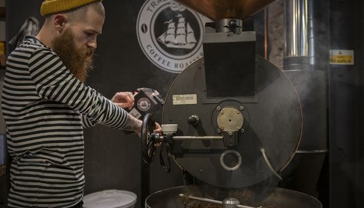 Trading Post Coffee. Brighton Coffee Shop Guide . A barista in a stripy top and beanie roasting coffee.