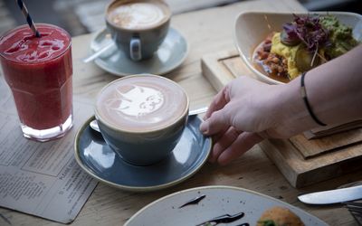 Latte art and juices served at the table with a bowl of food