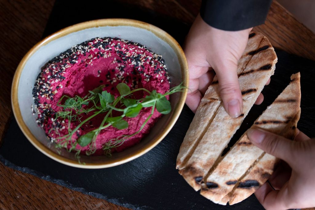 Beetroot infused hummus with blackened sesame seeds served with seared pitta bread. - Calamari fritti in a light peppery batter served with our black squid ink garlic mayonnaise