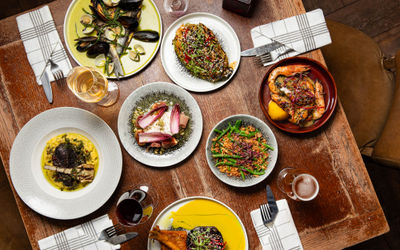 over head shot of the delicious and rich Bohemia dishes served on wooden table with glasses of wine and beer