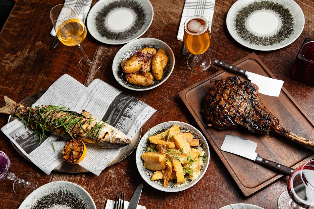 over head shot of the table laid out for two including dishes like fish, and meat, served with potatoes