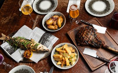 over head shot of the table laid out for two including dishes like fish, and meat, served with potatoes
