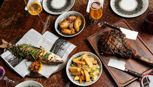 over head shot of the table laid out for two including dishes like fish, and meat, served with potatoes