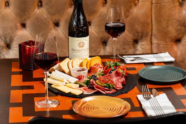 meat, cheese, chutney and crackers on the black charcuterie board, served with red wine. Bohemia Brightonj
