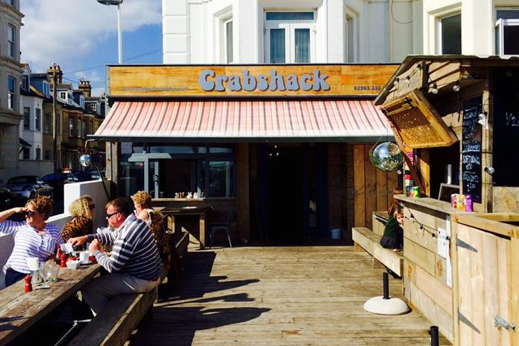 Exterior photo of The CrabShack, Sussex on a sunny day with people sitting outside eating.