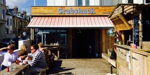 Exterior photo of The CrabShack, Sussex on a sunny day with people sitting outside eating.