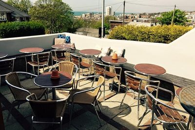 A sunny beer terrace with a view and tables.