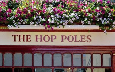 Exterior shot of The Hop Poles sign with summer flowers