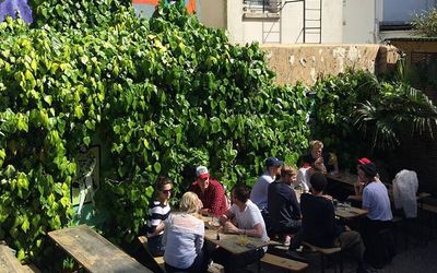 The beer garden with wooden tables and people drinking on a sunny